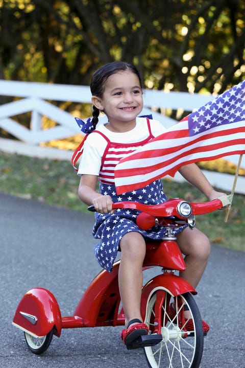 Child riding patriotic bicycle with American flag child riding patriotic bicycle with american flag