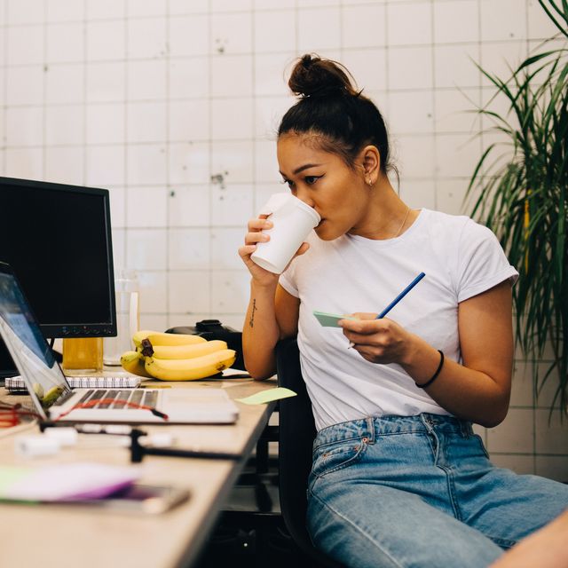 jonge vrouw drinkt koffie achter bureau