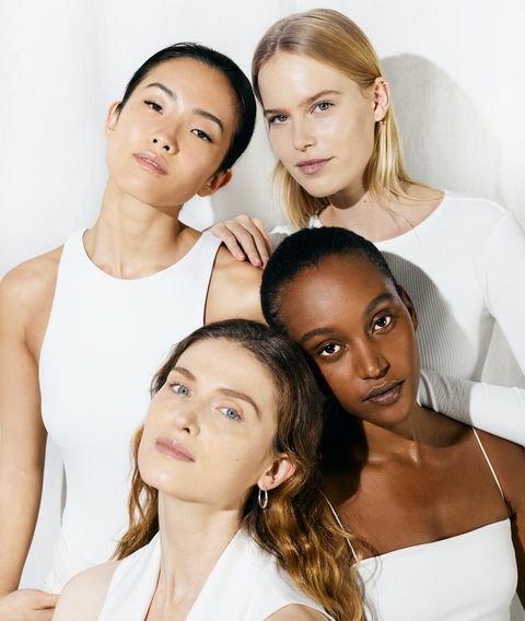 vier modellen in witte tops poseren voor foto