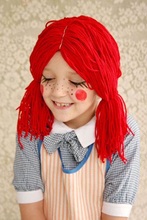 little girl dressed as rag doll in red yarn wig
