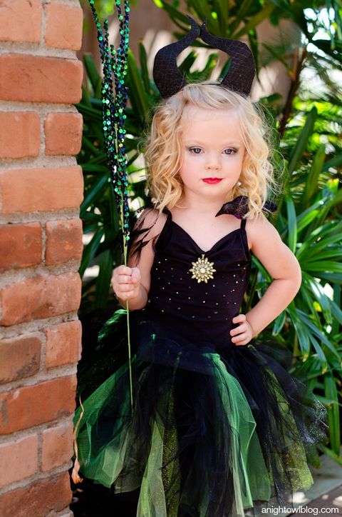 little girl in black horns wearing a black and green tulle skirt with a black and green sparkly staff