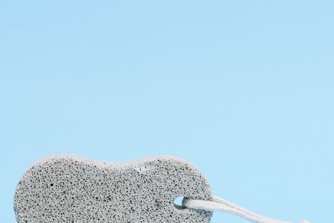 foot care tool a pumice stone for washing, removing callus from the foot, isolated on a light blue background