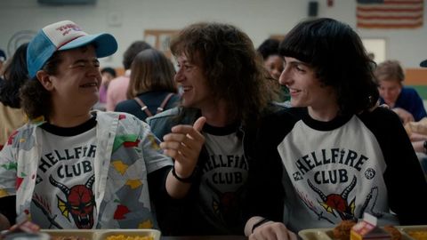 dustin, eddie and mike wear hellfire club tee shirts in a scene fro stranger things