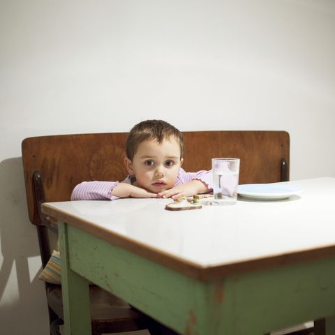 a young kid sits at a table with here food