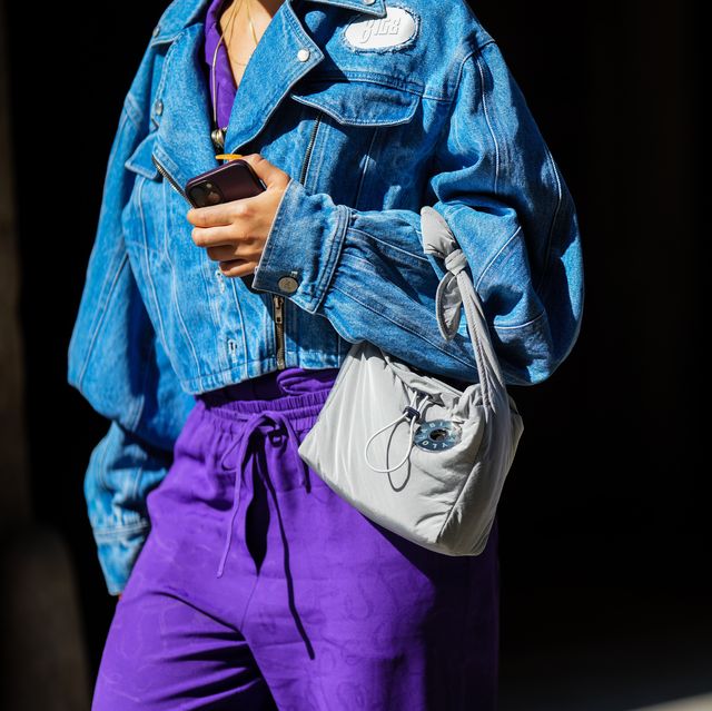 milan, italy september 22 a guest wears a purple flowing jumpsuit, a blue faded denim oversized bomber coat from 8igb, a white nylon handbag, outside dsquared2, during the milan fashion week womenswear springsummer 2023 on september 22, 2022 in milan, italy photo by edward berthelotgetty images