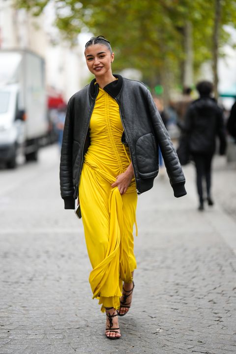 paris, france october 03 a guest wears a black shiny leather bomber coat, a yellow wrap ruffled long dress, black shiny leather heels sandals , outside stella mccartney, paris fashion week womenswear springsummer 2023, on october 03, 2022 in paris, france photo by edward berthelotgetty images