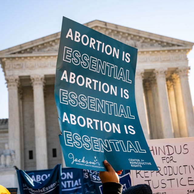 Supreme Court Hears Mississippi Abortion Case someone holding a sign in front of the supreme court that says abortion is essential
