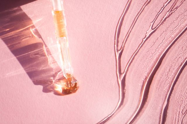 from above closeup glass pipette placed near smears of transparent gel on pink background beauty product of the year