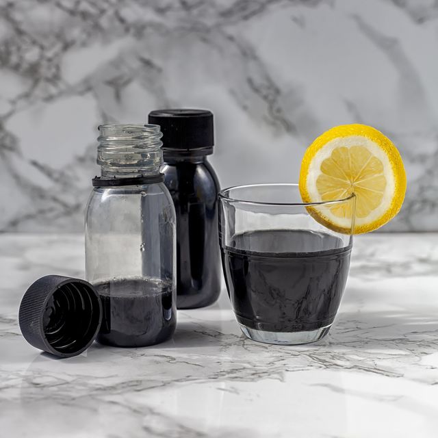 Activated charcoal detox juice drink or black lemonade whit coconut, green apple and lime on white marble background