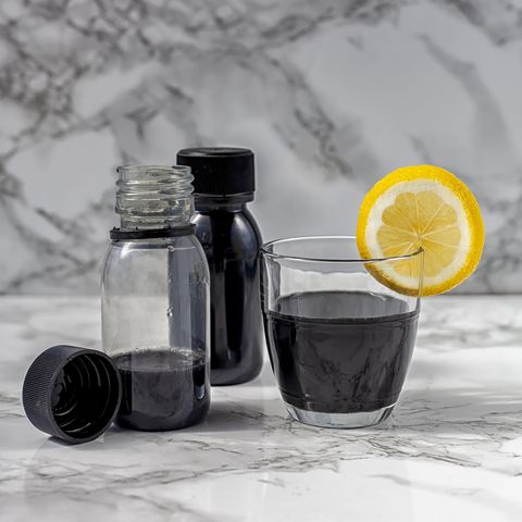 activated charcoal detox juice drink or black lemonade whit coconut, green apple and lime on white marble background