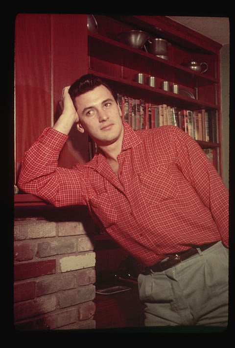 rock hudson leaning on a fireplace mantle