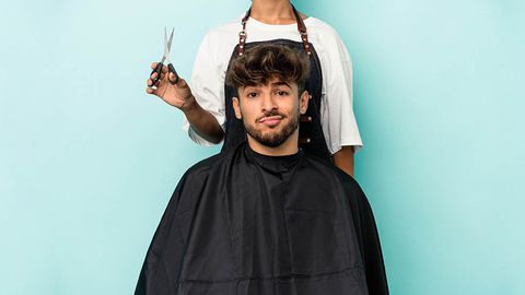 young arab man ready to get a haircut isolated on blue background confused, feels doubtful and unsure