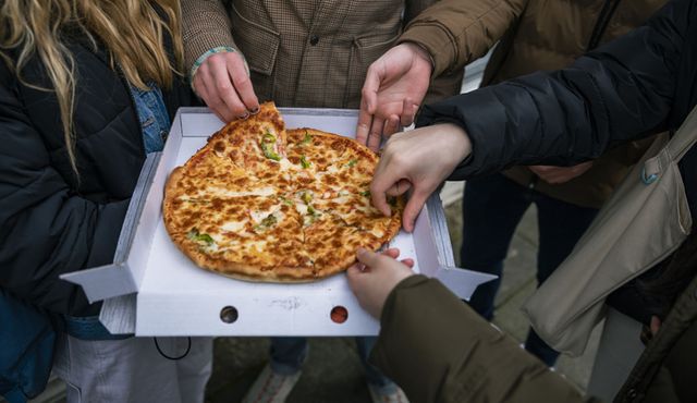 un grupo de adolescentes come una pizza