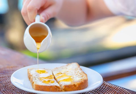 Adult men pouring honey to bread slices