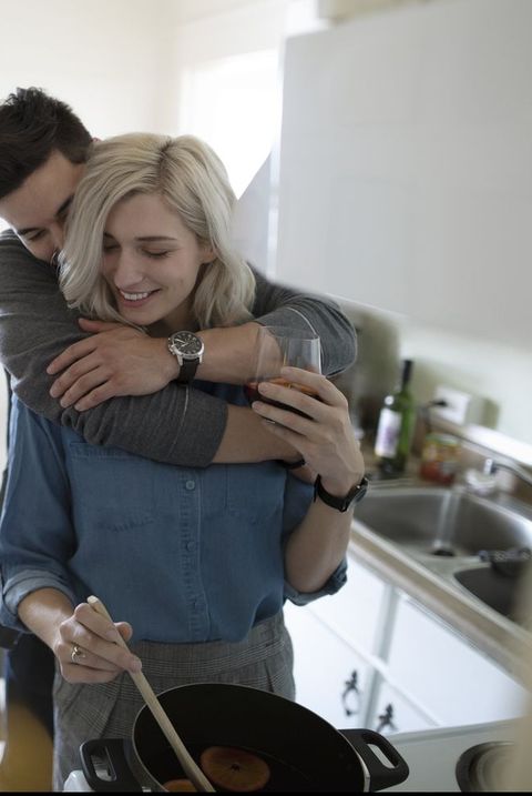 Affectionate young couple hugging, cooking in apartment kitchen
