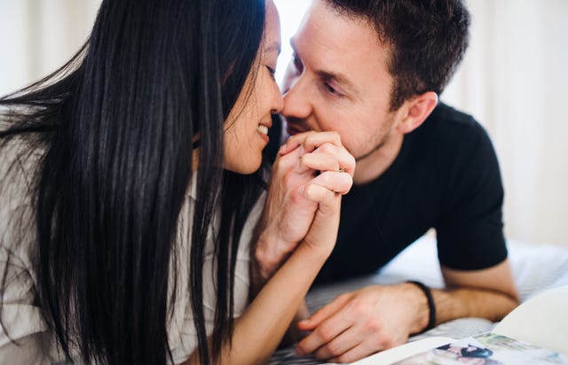 jeune couple affectueux et amoureux allongé sur un lit à la maison, discutant