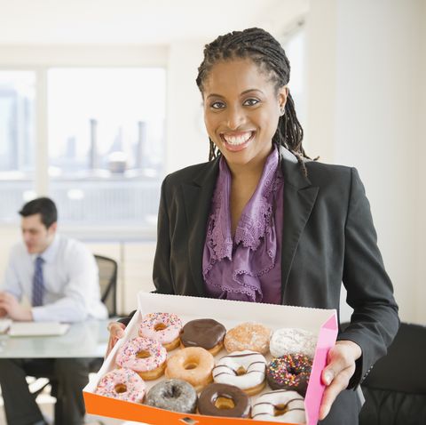 african american businesswoman carrying box of donuts