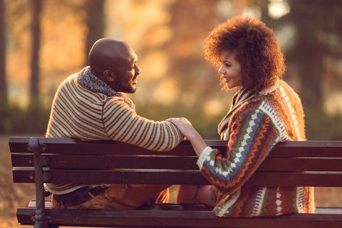 African American couple relaxing on bench and communicating in nature.