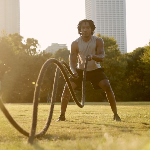 African-American man working out with battle ropes in field