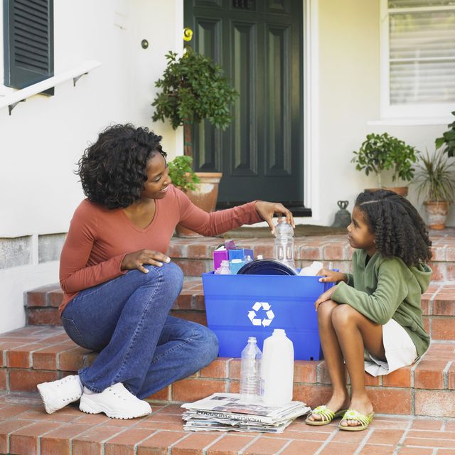 African American mother and daughter filling recycling bin