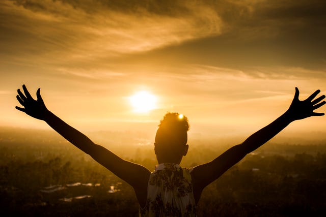 African American Woman Raising Arms at Sunset