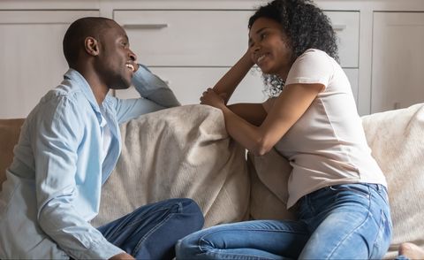 African couple in love sitting on couch chatting feels happy