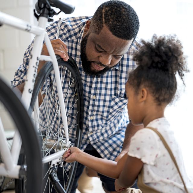 african father and daughter are fixed a bicycle together adjusting tightening a bicycle wheel at home
