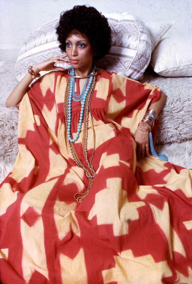 portrait of an unidentified model, in a red and yellow print dress accented with gold and turquoise jewelry, as she poses on a set of neutral colored throw pillows, new york, 1970s photo by anthony barbozagetty images