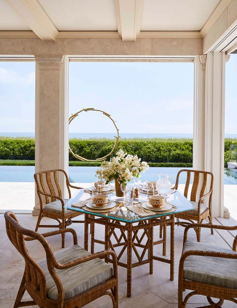 a small dining table with four chairs on a poolside terrace