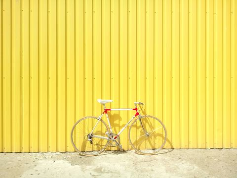 Bicycle, Yellow, Bicycle part, Wall, Bicycle wheel, Vehicle, Line, Bicycle handlebar, Bicycle accessory, Bicycle frame, 