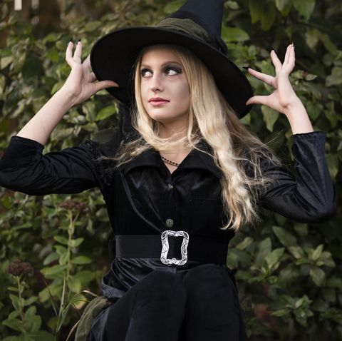 teentween girl dressed in black witch halloween costume near greenery