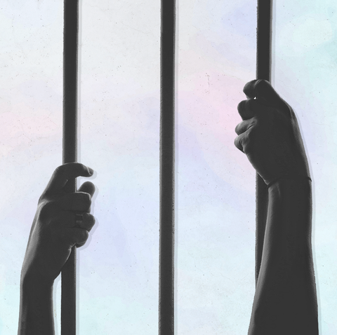 two hands reaching up to hold prison bars