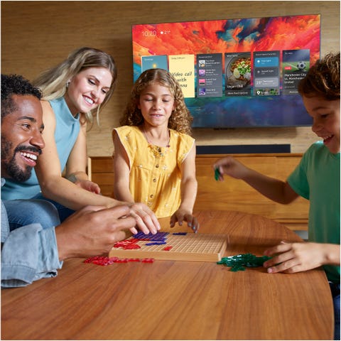 amazon fire tv omni qled on wall behind family playing games
