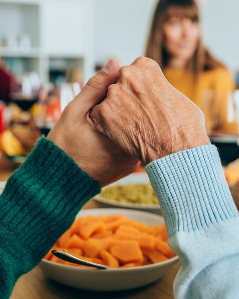 close up shot of a people holding hands in prayer before having a holiday dinner or lunch