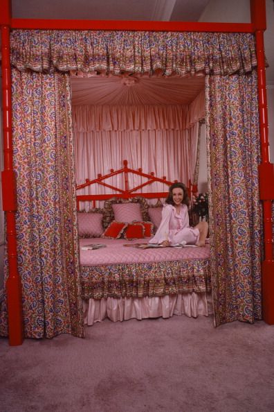 helen gurley brown on pink bed with paisley curtains