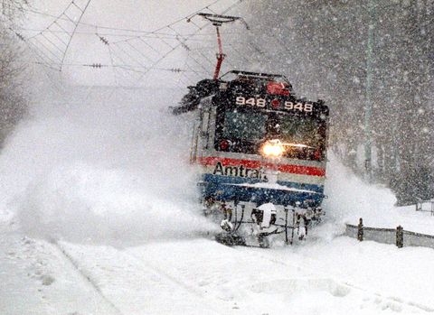 An Amtrak train blasts through a snow drift, as it runs thro