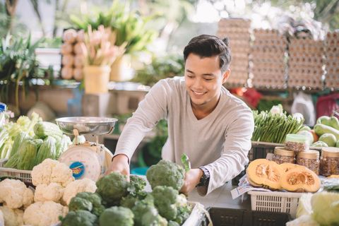 Proprietario al dettaglio di verdure malese asiatico che organizza le sue verdure in preparazione per gli affari