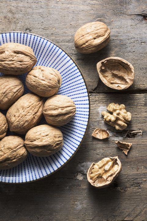 An overhead bowl of walnuts on a rough wooden background