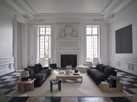 a white living room with two black sofas surrounding a coffee table