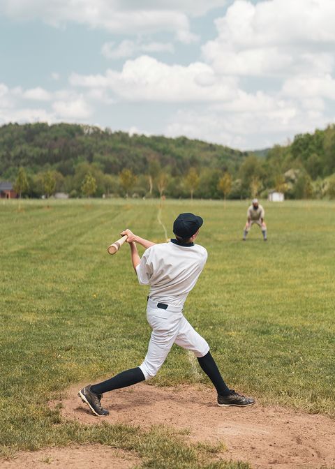 vintage base ball association player swinging bat on all grass field