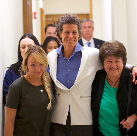 andrea constand with her lawyers wearing a white blazer and blue top walking through court