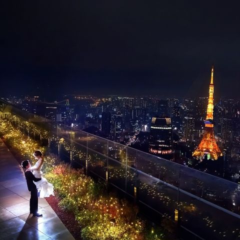 「アンダーズ 東京」のルーフトップの夜景をバックに佇む新郎新婦の写真。