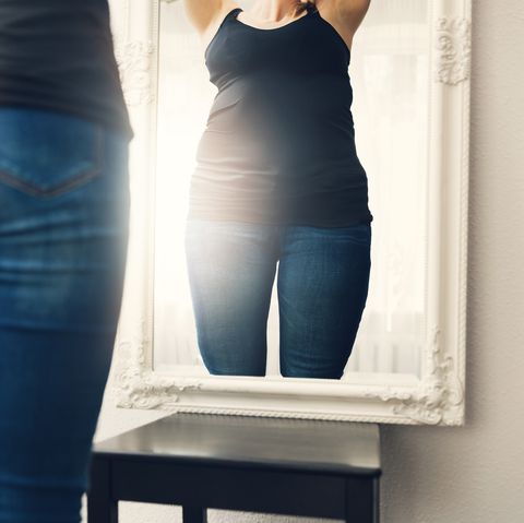 anorexia concept - woman looks at her fat reflection in mirror