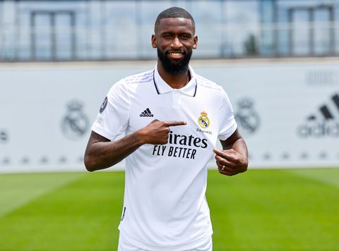 antonio rudiger smiles and points to the club badge on his real madrid shirt