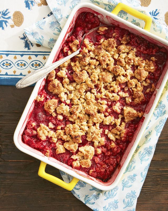 berry fruit crisp in a baking dish with a serving spoon on a table with a blue tablecloth
