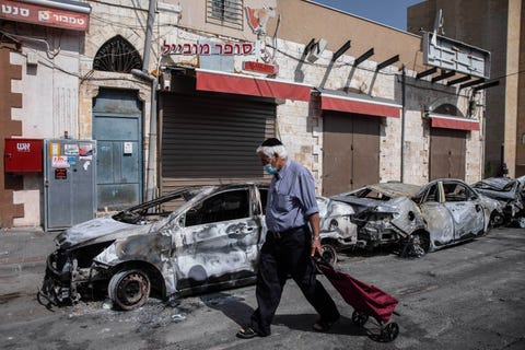 man walking by a burned car