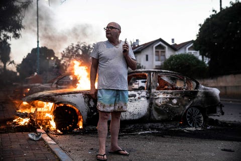 man in flip flops in front of a burning car