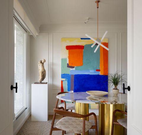 comedor con mesa con sobre de mármol y estructura de latón y cuadro abstracto en la pared