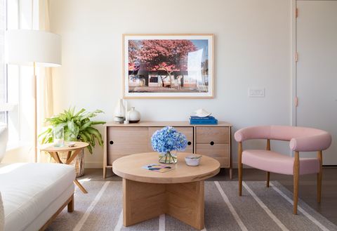 salón de diseño mid century con mesa de centro de madera redonda y butaca rosa