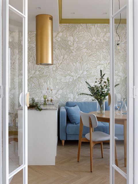 cocina, salón y comedor con papel pintado floral y sofá azul